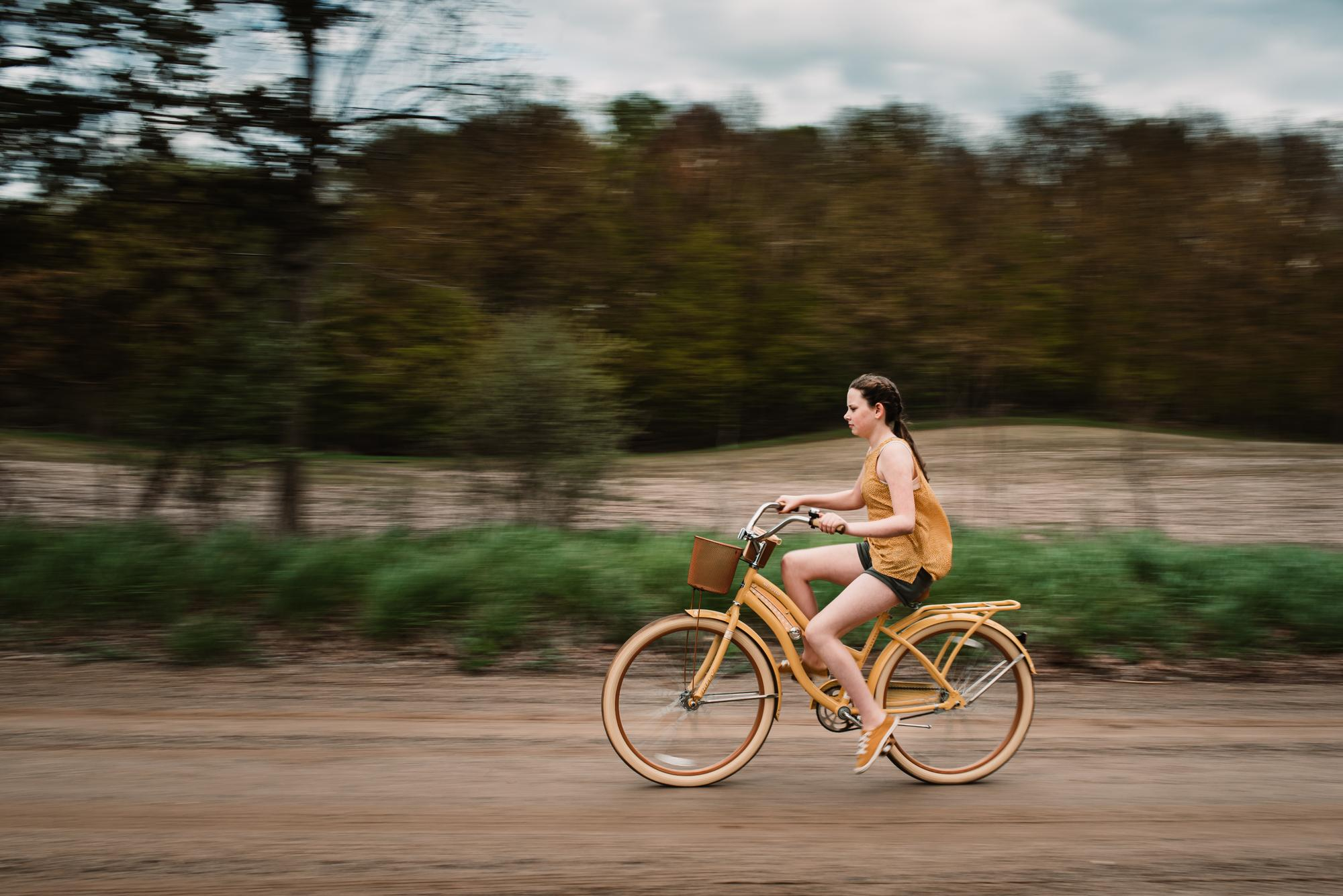 girl-riding-her-yellow-bike-dirt-road-summer